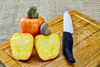 Fresh cashew fruit. Cashew, aka, caju, typical Brazilian fruit rich in vitamin C and zinc, cut in half on a wooden cutting board w