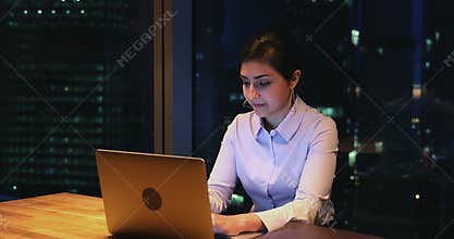 Indian businesswoman working overhours on laptop in office at night