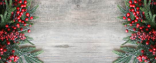 Christmas Background with Rustic Evergreen Pine Branches and Red Berries Over Wood Texture