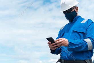 Marine seaman or bosun on deck of vessel or ship. He is speaking on the mobile cell phone