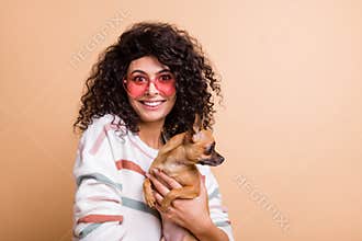 Photo of young attractive latin woman happy smile wear sunglass hold little friend dog isolated over beige color