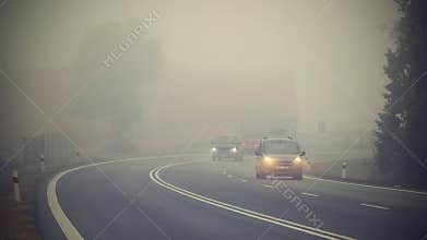 Car on the road in the fog. Autumn landscape - dangerous road traffic in winter season