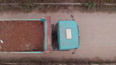 Aerial view, construction truck transporting soil through a dirt path . Activity machine in building business. Top view from drone