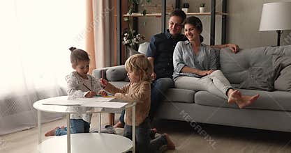 Happy parents relaxing on couch children drawing in sketchbook
