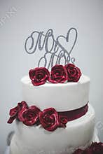 Vertical shot of a wedding cake with dark red roses and Mr and Mrs writings