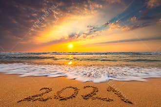 Happy New Year 2021, lettering on the beach. Written text on the sea beach at sunrise