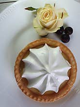 Cake with white cream in a saucer with rose and berries On a white background Close-up