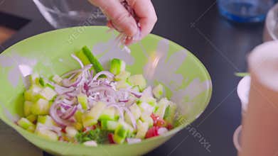 Close up view of red onion being added to salad bowl. Healthy food concept.