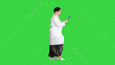 Female doctor examining lungs x-ray while walking on a Green Screen, Chroma Key.