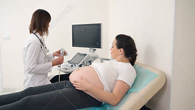 Doctor using ultrasound for scanning tummy of pregnant woman