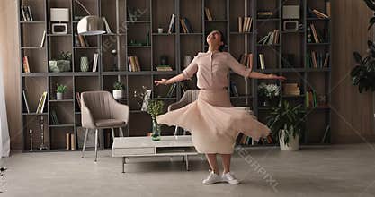 Happy young indian woman dancing alone indoors.