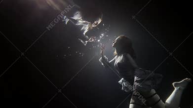 Young woman is floating underwater and touching reflection in surface, magic slow motion shot in pool