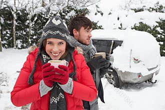 Young couple in snow with car