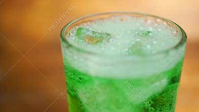 Air bubbles inside glass of sparkling green soda water