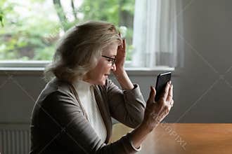 Confused senior 60s woman holding head, feeling dizziness