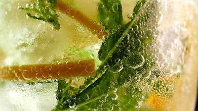 Refreshing soft drink with ice. Mojito with lemon and mint in a glass. Carbonated water close up. Drops of cold dew on a