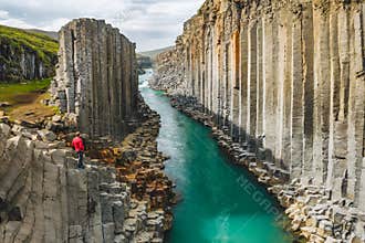 Man hiker in red jacket visit Studlagil basalt canyon, with rare volcanic basalt column formations, Iceland