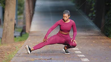 Portrait of african american sporty woman doing stretching exercises in park before training. Female athlete preparing
