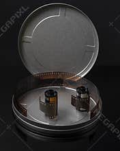 Two old rolls of analog photographic film in a circular tin container with the cap open and some negatives inside