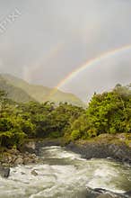 Double rainbow over a river in tropical forest in Banos, Ecuador