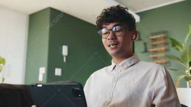 Mixed race male interacting with class mates online learning waving to students while working from home