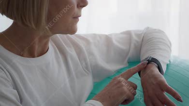 Unrecognizable Senior Woman Using Smartwatch During Workout Sitting Indoors