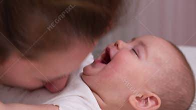 Close up mother kissing happy baby laughing enjoying loving mom nurturing toddler at home.