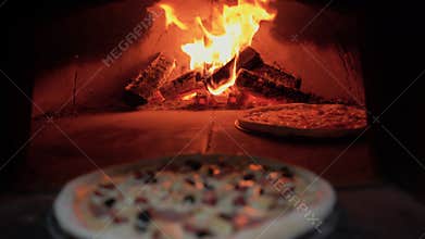 Baking pizza in a wood-fired oven. The baker takes a fresh pizza out of the fire. Italian pizza cooking