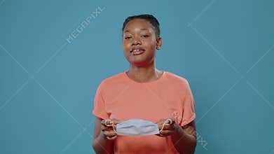 Casual woman removing face mask off of face and taking breath