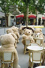 Vertical shot of Teddy bears of Gobelins sitting at the tables at a cafe in Paris outdoors