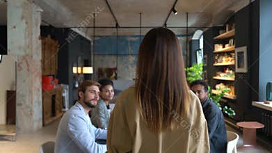Rear view of a female entrepreneur walking to the conference table with colleagues