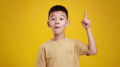 Kids and creative thinking. Adorable little asian boy having great idea, pointing finger up, expressing eureka