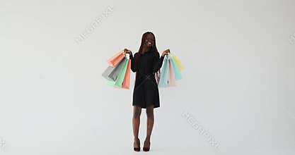 Woman with long braided hair holding shopping bags and dancing