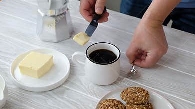 Person making keto coffee with butter and MCT oil at home, biohacking receipt