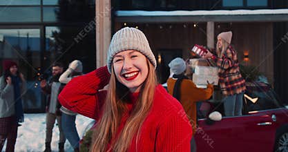 Portrait of young beautiful happy blonde woman in red sweater smile at camera at fun Christmas friends party slow motion