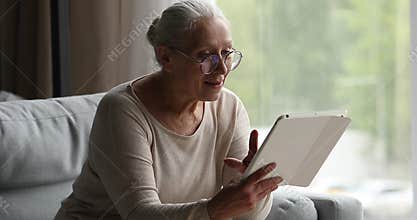 Happy retired lady aged 60 years networking on touchpad device