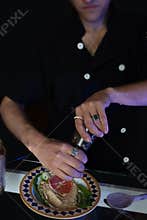 Man seasoning a chickpea pasta starter.