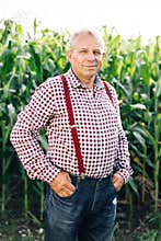 Portrait of Senior Caucasian handsome happy man farmer standing in corn field and smiling to camera. Cheerful male