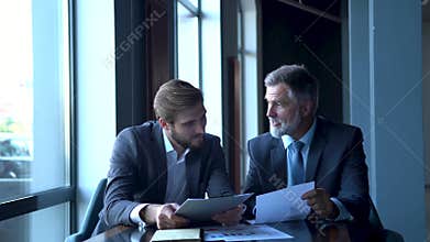 Two happy successful businessmen discussing company development strategy at brainstorming meeting in office