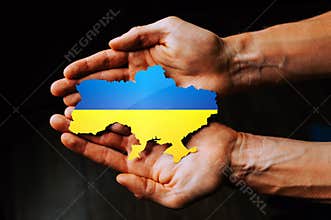 Support for Ukraine in the war with Russia. Hands holding the flag of Ukraine in the shape of the borders of Ukraine