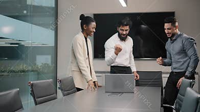 Excited happy business team multiracial people group in office looking at laptop celebrate corporate success winning