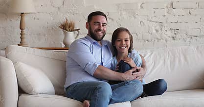 Happy father embrace son sitting on couch look at camera