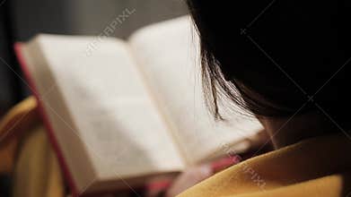 Top view of woman is reading book in evening, turning page. Close-up