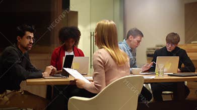Remote view of young startup team of diverse young business people working sitting at table with laptop in modern office