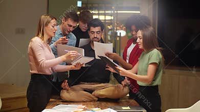 Calm male team leader sitting on office table in lotus position with closed eyes and meditating feeling calmness and