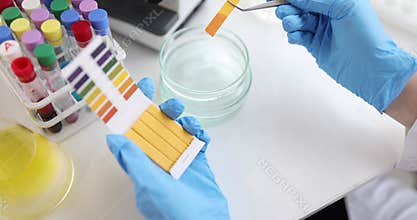 Scientist using PH test kit to test water in glass cup closeup