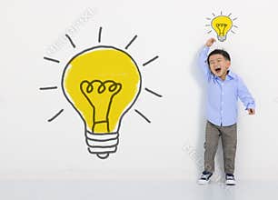 Child student thinking and light bulb on the white wall . Cute little boy has an new idea. Innovation technology and education con
