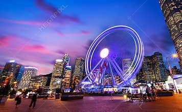 Spinning Ferris Wheel in Motion at Central Pier in Hong Kong During Sunset Blue Hour With Moving Clouds