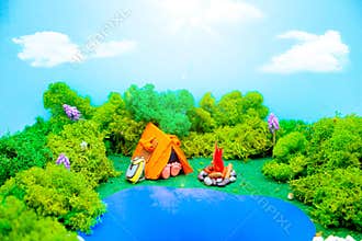 Plasticine landscape with a tent, a campfire and a backpack in the middle of the forest