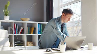 Young male entrepreneur works at home office at the computer. Workplace of freelancer or student. Remote work and